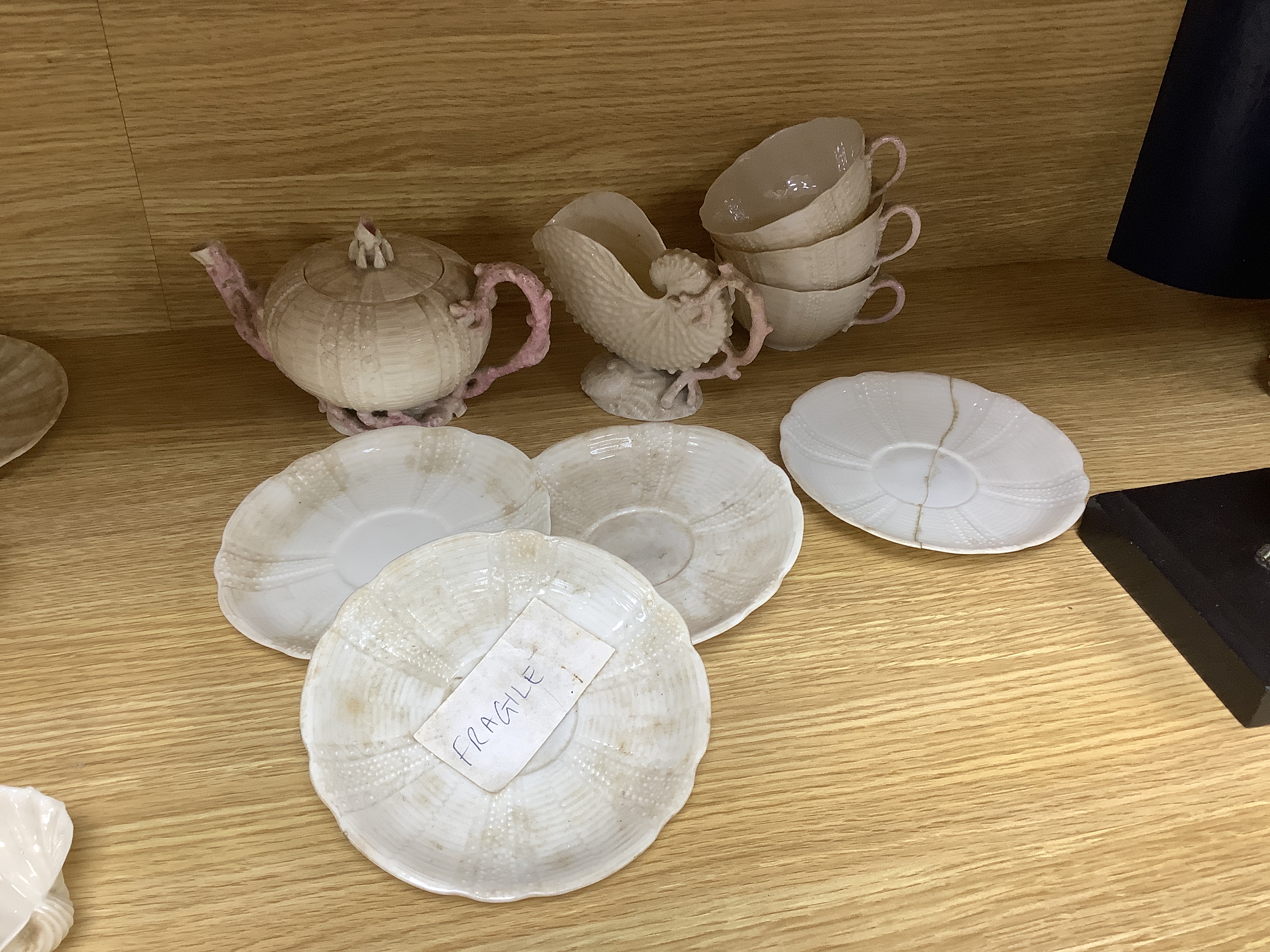 A quantity of Belleek including a teapot, three cups and saucers and a shell design vase, mostly first period